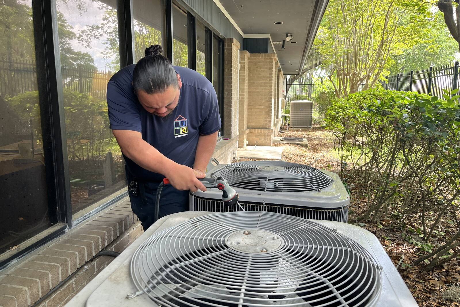 Ideal Conditions technician servicing a heat pump outside a Northeast Florida home