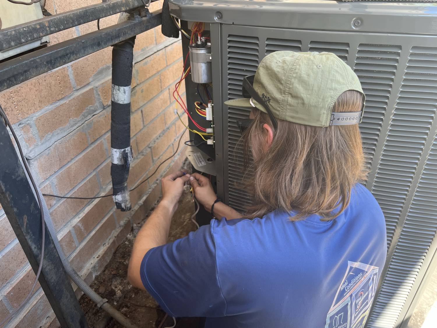 Ideal Conditions technician wiring a new heat pump condenser on a Jacksonville install